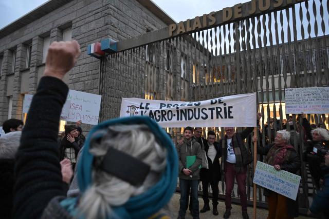 Defendants and their relatives hold banners and placards outside the Lorient courthouse ahead of the trial of 12 environmental activists from the Brittany Against Factory Farms collective for blocking a freight train in Lorient, western France, on December 15, 2025. (Photo by Damien MEYER / AFP)