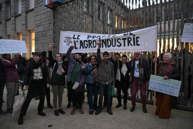 Defendants and their relatives hold banners and placards outside the Lorient courthouse ahead of the trial of 12 environmental activists from the Brittany Against Factory Farms collective for blocking a freight train in Lorient, western France, on December 15, 2025. (Photo by Damien MEYER / AFP)