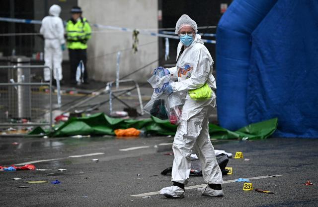 (FILES) A police forensics officer carries items bagged for evidence as they work at the scene on Water Street in Liverpool, north-west England on May 27, 2025, where a car ploughed in to crowds that had gathered on May 26 to watch an open-top bus victory parade for Liverpool's Premier League trophy parade. The sentencing hearing for British man Paul Doyle who ploughed his car through crowds of fans celebrating Liverpool's Premier League victory in May, injuring over 100 people, is set to begin on December 15, 2025. (Photo by Paul ELLIS / AFP)
