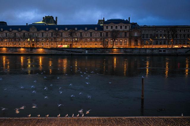 This photograph shows gulls flying over the river Seine at dawn opposite the Louvre Museum, in Paris on December 15, 2025. (Photo by Blanca CRUZ / AFP)