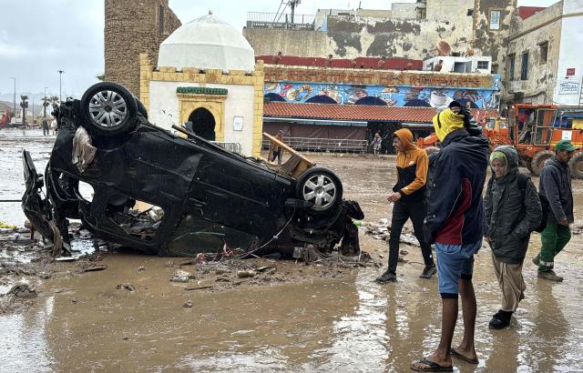 Moroccans looks at a destroyed vehicle and other debris following a flash flood, in the coastal town of Safi, some 300 kilometres (186 miles) south of the capital Rabat on December 15, 2025. A flash flood and a muddy torrent in the Moroccan coastal town killed at least 37, local officials said December 15, as search and rescue operations continued. Drought-hit Morocco often faces severe weather, but the flooding in Safi is already the deadliest such disaster in at least a decade. (Photo by AFP)