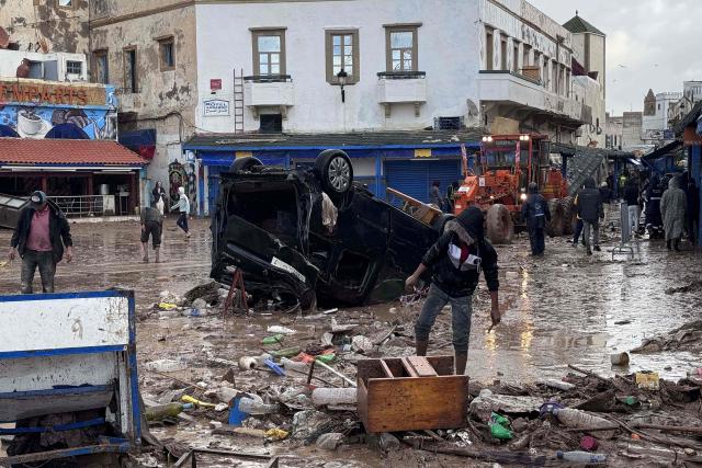 Moroccans looks at a destroyed vehicle and other debris following a flash flood, in the coastal town of Safi, some 300 kilometres (186 miles) south of the capital Rabat on December 15, 2025. A flash flood and a muddy torrent in the Moroccan coastal town killed at least 37, local officials said December 15, as search and rescue operations continued. Drought-hit Morocco often faces severe weather, but the flooding in Safi is already the deadliest such disaster in at least a decade. (Photo by AFP)