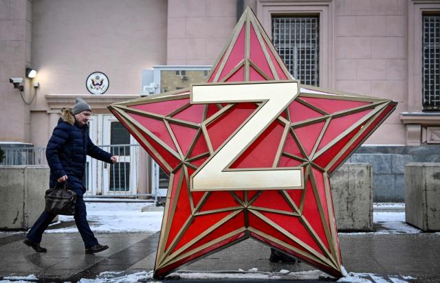 A man walks past a New Year decoration - the Kremlin star, bearing a Z letter, a tactical insignia of Russian troops in Ukraine, installed in front of the US Embassy in Moscow on December 15, 2025. US negotiators still want Ukraine to cede control of the eastern Donetsk and Lugansk regions as a condition for peace talks with Russia, an official briefed on the discussions told AFP on Monday. Kyiv is pushing back against Washington's demand that it pull troops from the two regions collectively known as Donbas, which Russia has been unable to capture since invading in February 2022. (Photo by Alexander NEMENOV / AFP)