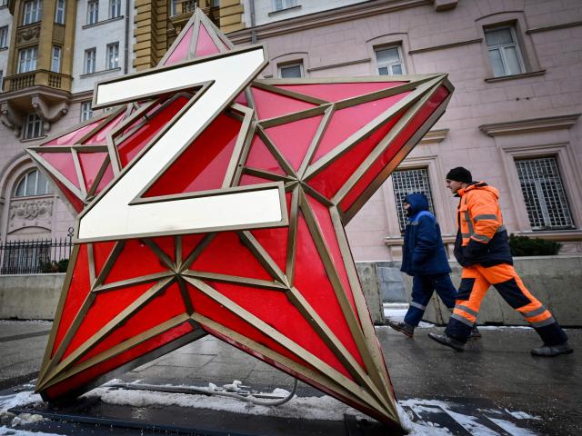 Municipal workers walk past a New Year decoration - the Kremlin star, bearing a Z letter, a tactical insignia of Russian troops in Ukraine, installed in front of the US Embassy in Moscow on December 15, 2025. US negotiators still want Ukraine to cede control of the eastern Donetsk and Lugansk regions as a condition for peace talks with Russia, an official briefed on the discussions told AFP on Monday. Kyiv is pushing back against Washington's demand that it pull troops from the two regions collectively known as Donbas, which Russia has been unable to capture since invading in February 2022. (Photo by Alexander NEMENOV / AFP)