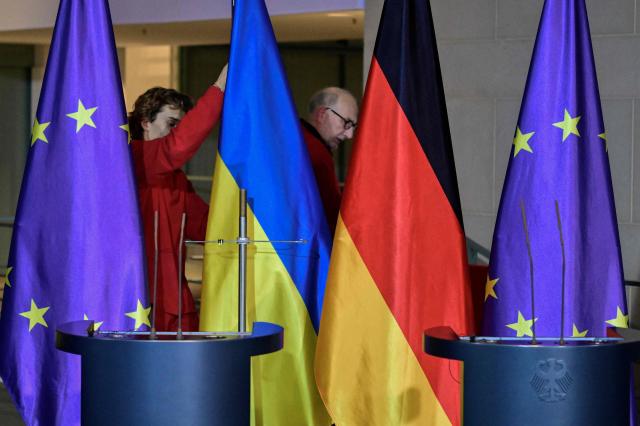 Workers install the Ukrainian and the German flag ahead a press conference of the German Chancellor and Ukraine's President at the Chancellery in Berlin, Germany, on December 15, 2025. Ukrainian President Volodymyr Zelensky travelled to Berlin to meet European leaders as well as US President Donald Trump's envoy, heads of the EU and of the NATO for talks on how to end the grinding war with Russia. (Photo by John MACDOUGALL / AFP)