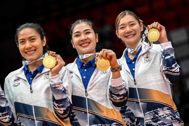 Thailand's players showing their gold medals pose for photographs after winning the women's volleyball final match of the 33rd Southeast Asian Games (SEA Games) against Vietnam at Huamark Indoor Stadium in Bangkok on December 15, 2025. (Photo by Chanakarn Laosarakham / AFP)