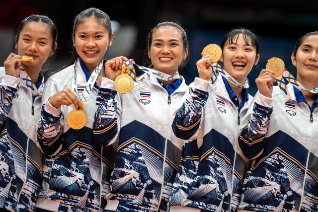 Thailand's players showing their gold medals pose for photographs after winning the women's volleyball final match of the 33rd Southeast Asian Games (SEA Games) against Vietnam at Huamark Indoor Stadium in Bangkok on December 15, 2025. (Photo by Chanakarn Laosarakham / AFP)