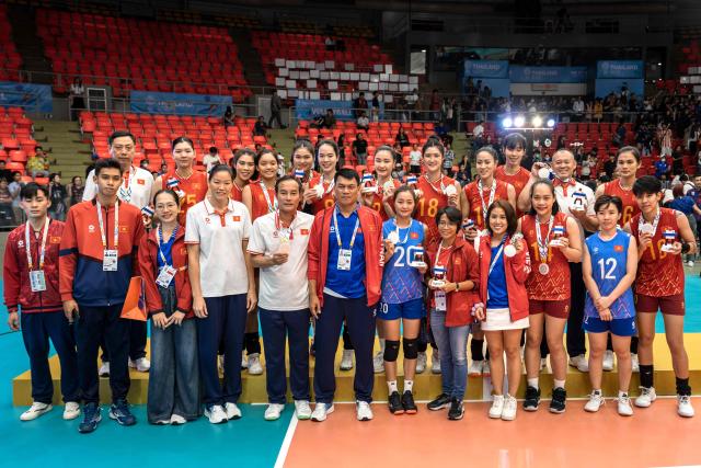 Vietnam's players showing their silver medals pose for photographs after the women's volleyball final match of the 33rd Southeast Asian Games (SEA Games) against Thailand at Huamark Indoor Stadium in Bangkok on December 15, 2025. (Photo by Chanakarn Laosarakham / AFP)