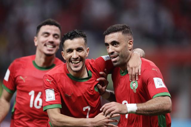 Morocco's forward #9 Abderrazzaq Hamed Allah (R) celebrates after scoring his team's third goal with Morocco's defender #7 Mohamed Boulacsout (C) and Morocco's midfielder #16 Achraf Al Mahdioui (L) during the FIFA Arab Cup 2025 semi-final football match between Morocco and the United Arab Emirates at the Khalifa International Stadium in Al-Rayyan on December 15, 2025. (Photo by KARIM JAAFAR / AFP)