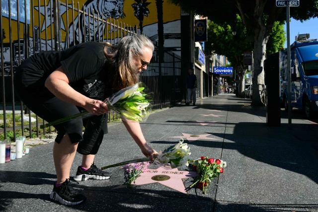 A woman places flowers at US actor and director Rob Reiner's Star on the Hollywood Walk of Fame in Los Angeles, California, on December 15, 2025. Reiner's son was charged with murder, police said on December 15, after his father and mother were found dead the previous day in their Los Angeles home. (Photo by Frederic J. Brown / AFP)