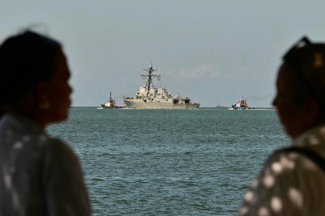 (FILES) People watch the USS Gravely, a US Navy warship, departing the Port of Port of Spain on October 30, 2025. The Caribbean nation of Trinidad and Tobago said on December 15, 2025, it had authorized US military aircraft to use its airports amid growing fears Washington may be preparing an attack on nearby Venezuela. (Photo by MARTIN BERNETTI / AFP)