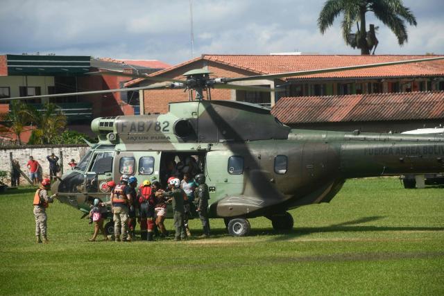 People rescued by helicopter after the Pirai River overflowed due to heavy rains arrive at the Municipal Coliseum in El Torno, Santa Cruz department, Bolivia on December 15, 2025. At least 20 people were killed and dozens remain missing after a major river in eastern Bolivia burst its banks at the weekend following heavy rains, authorities said Monday. (Photo by Rodrigo URZAGASTI / AFP)