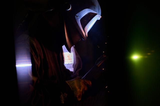 A welder works on a part of a snowplow at Arctic Snowplows in London, Ontario, on December 10, 2025. For decades, Arctic Snowplows has sold its Canadian-made galvanized steel products to "anywhere there is snow" across the border in the United States, says company boss Mike Schulz. But a year into President Donald Trump's trade war, some of those customers have been lost, with buyers unwilling to stomach higher prices forced by US tariffs on imported steel. "Adding an extra $500 (US$363) on the cost of a $10,000 plow, it's a huge hit," Schulz told AFP, as a heavy snow fell outside the company's factory in London, Ontario, 190 kilometers (120 miles) southwest of Toronto. (Photo by Geoff Robins / AFP)
