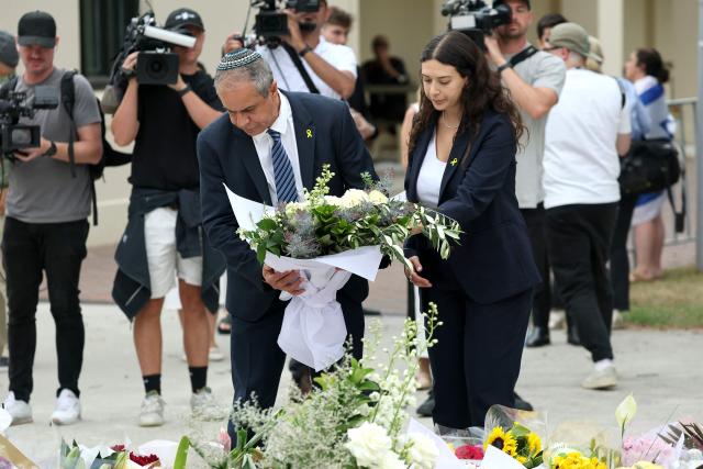 Israeli Ambassador to Australia Amir?Maimon (L) lays flowers at the Bondi Pavilion memorial in Sydney on December 16, 2025, honoring the victims of the Bondi Beach shooting. A father-and-son team toting long-barrelled guns shot and killed 15 people including a 10-year-old girl at Sydney's Bondi Beach on December 14, with authorities labelling it an antisemitic terrorist attack on a Jewish festival. (Photo by DAVID GRAY / AFP)