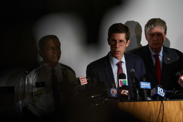 Providence Mayor Brett Smiley, flanked by Chief of Police Colonel Oscar Lopez (L) and Rhode Island Governor Daniel McKee (R) answers questions from reporters during a press conference into the ongoing investigation into the December 13 mass shooting at Brown University, at the Providence Public Safety Complex in Providence, Rhode Island, on December 15, 2025. A gunman remained at large after a weekend mass shooting at elite Brown University left two dead and nine wounded, with US authorities releasing new footage of a masked "person of interest" captured on surveillance cameras. The shooting took place Saturday in a building where exams were underway on the Ivy League campus in Providence, Rhode Island when a man with a rifle burst in and opened fire before fleeing. (Photo by Bing Guan / AFP)
