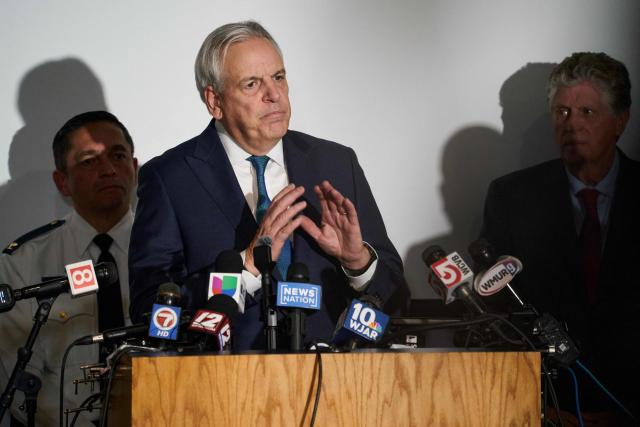 Rhode Island Attorney General Peter Noronha (C) speaks during a press conference into the ongoing investigation into the December 13 mass shooting at Brown University, at the Providence Public Safety Complex in Providence, Rhode Island, on December 15, 2025. A gunman remained at large after a weekend mass shooting at elite Brown University left two dead and nine wounded, with US authorities releasing new footage of a masked "person of interest" captured on surveillance cameras. The shooting took place Saturday in a building where exams were underway on the Ivy League campus in Providence, Rhode Island when a man with a rifle burst in and opened fire before fleeing. (Photo by Bing Guan / AFP)