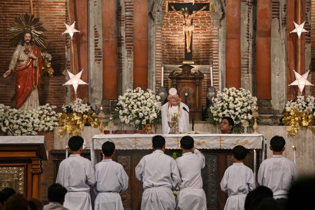 A Roman Catholic priest leads the first of nine dawn masses, known as "Misa de Gallo", at a church in Las Pinas, suburban Manila on December 16, 2025, to signal the official start of the Christmas season. (Photo by Ted ALJIBE / AFP)