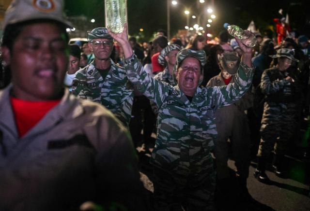 A member of the Bolivarian militia and supporter of Venezuela's President Nicolas Maduro shouts slogans during a rally demanding peace in Caracas on December 15, 2025. The Caribbean nation of Trinidad and Tobago said on December 15, 2025, it had authorized US military aircraft to use its airports, amid growing fears Washington may be preparing an attack on nearby Venezuela. (Photo by Juan BARRETO / AFP)