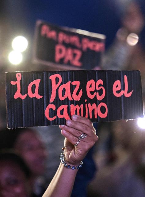 A supporter of Venezuela's President Nicolas Maduro holds a sign during a rally demanding peace in Caracas on December 15, 2025. The Caribbean nation of Trinidad and Tobago said on December 15, 2025, it had authorized US military aircraft to use its airports, amid growing fears Washington may be preparing an attack on nearby Venezuela. (Photo by Juan BARRETO / AFP)
