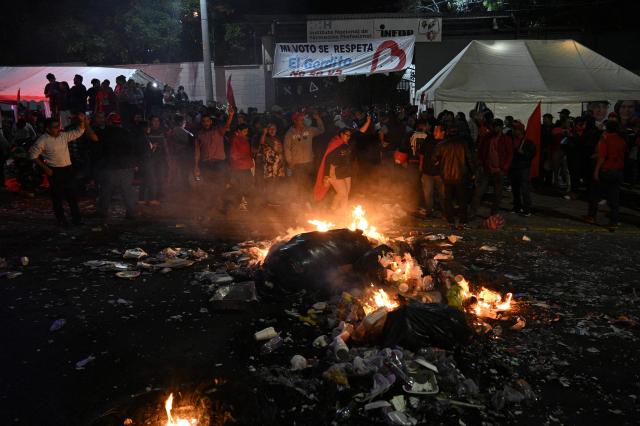 Supporters of the ruling Libertad y Refundacion (LIBRE) party burn trash during a protest to denounce electoral fraud in the last election in Tegucigalpa on December 15, 2025. Observers from the Americas and Europe said on December 15, 2025, there was no reason to suspect fraud in the recent Honduran election but criticized a sluggish vote count, as US President Donald Trump's preferred candidate maintained a slim lead. (Photo by Orlando SIERRA / AFP)