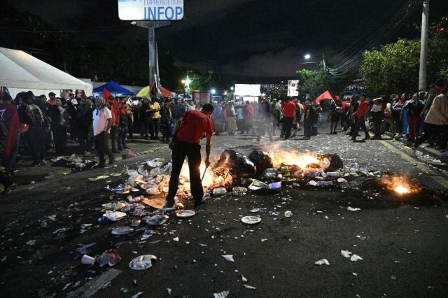 Supporters of the ruling Libertad y Refundacion (LIBRE) party burn trash during a protest to denounce electoral fraud in the last election in Tegucigalpa on December 15, 2025. Observers from the Americas and Europe said on December 15, 2025, there was no reason to suspect fraud in the recent Honduran election but criticized a sluggish vote count, as US President Donald Trump's preferred candidate maintained a slim lead. (Photo by Orlando SIERRA / AFP)