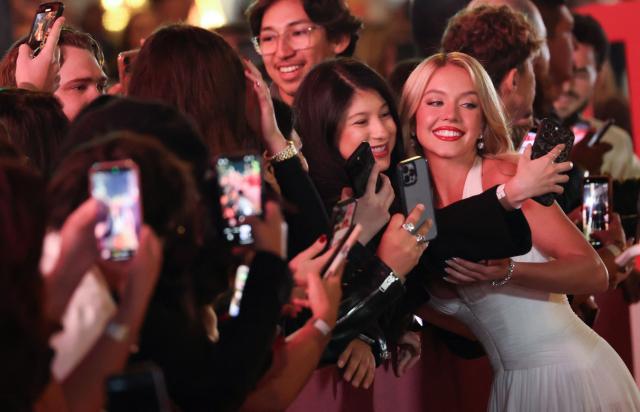 US actress Sydney Sweeney takes selfies with fans as she attends the LA premiere of Lionsgate's "The Housemaid" at the TCL Chinese theatre in Los Angeles, on December 15, 2025. (Photo by Patrick T. Fallon / AFP)