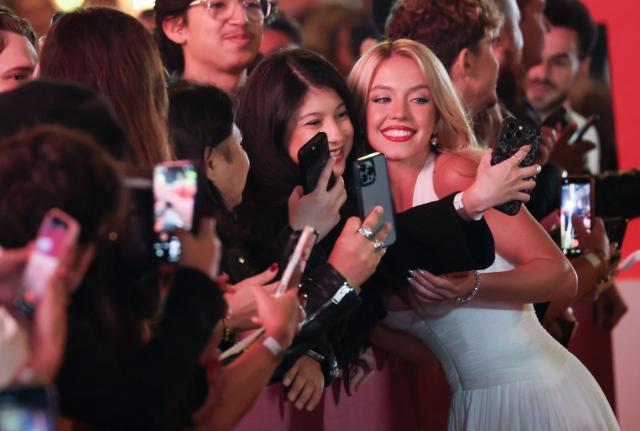 US actress Sydney Sweeney takes selfies with fans as she attends the LA premiere of Lionsgate's "The Housemaid" at the TCL Chinese theatre in Los Angeles, on December 15, 2025. (Photo by Patrick T. Fallon / AFP)