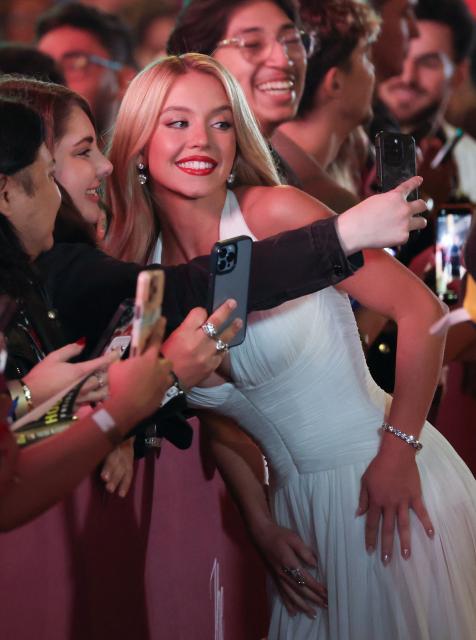 US actress Sydney Sweeney takes selfies with fans as she attends the LA premiere of Lionsgate's "The Housemaid" at the TCL Chinese theatre in Los Angeles, on December 15, 2025. (Photo by Patrick T. Fallon / AFP)
