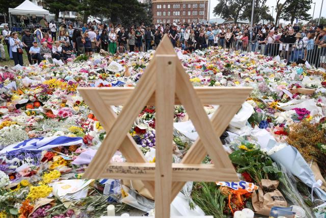 A wooden Star of David is seen as people gather around floral tributes outside Bondi Pavilion in Sydney on December 16, 2025, to honour victims of the Bondi Beach shooting. Australia's leaders have agreed to toughen gun laws after attackers killed 15 people at a Jewish festival on Bondi Beach, the worst mass shooting in decades decried as antisemitic "terrorism" by authorities. (Photo by DAVID GRAY / AFP)