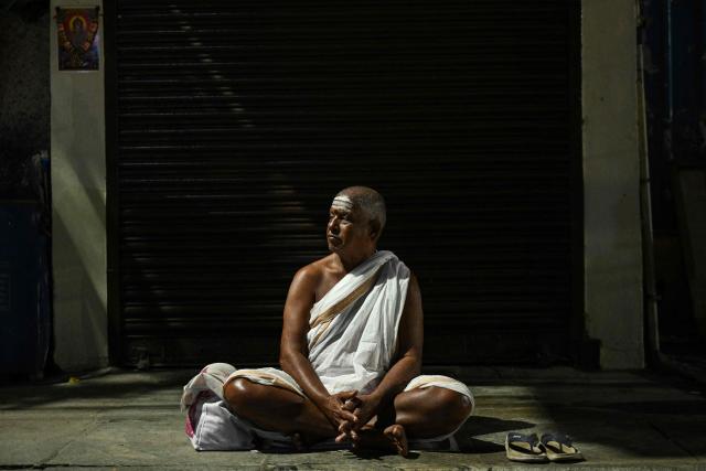 A Hindu priest waits to offer prayers outside a closed temple early morning at the Mylapore neighbourhood in Chennai on December 16, 2025. (Photo by R. Satish BABU / AFP)