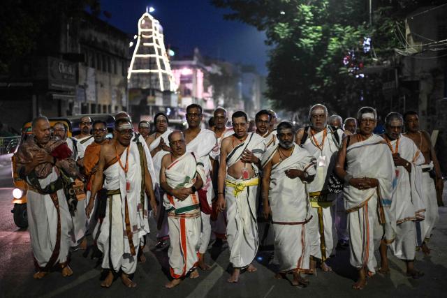 Hindu priests sing hymns and offer prayers as they walk past a temple early morning at the Mylapore neighbourhood in Chennai on December 16, 2025. (Photo by R. Satish BABU / AFP)