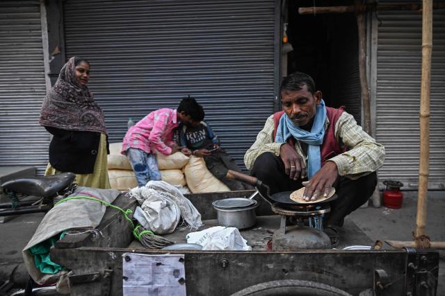 A man cooks bread on a cart in the old quaters of Delhi on December 16, 2025. (Photo by Arun SANKAR / AFP)