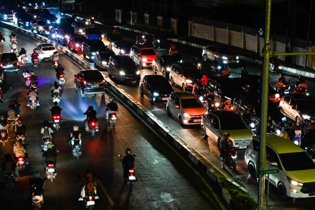 Motorists ride along a road with no traffic light or street light during a blackout in the aftermath of flash floods in Banda Aceh on December 15, 2025. Devastating floods and landslides have killed 1,006 people in Indonesia, rescuers said December 13 as the Southeast Asian nation grapples with the huge scale of relief efforts. (Photo by CHAIDEER MAHYUDDIN / AFP)