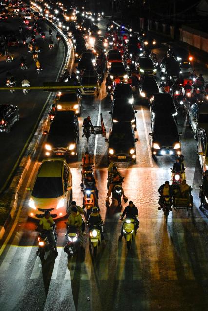 Motorists ride along a road with no traffic light or street light during a blackout in the aftermath of flash floods  in Banda Aceh on December 15, 2025. Devastating floods and landslides have killed 1,006 people in Indonesia, rescuers said December 13 as the Southeast Asian nation grapples with the huge scale of relief efforts. (Photo by CHAIDEER MAHYUDDIN / AFP)