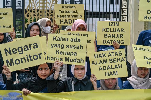 Activists hold placards as they take part in a protest demanding humanitarian releif for those affected by flash floods in Aceh, North Sumatra, and West Sumatra provinces, in front of the People's Representative Council of Aceh (DPRA) in Banda Aceh on December 16, 2025. Devastating floods and landslides have killed 1,006 people in Indonesia, rescuers said December 13 as the Southeast Asian nation grapples with the huge scale of relief efforts. (Photo by CHAIDEER MAHYUDDIN / AFP)