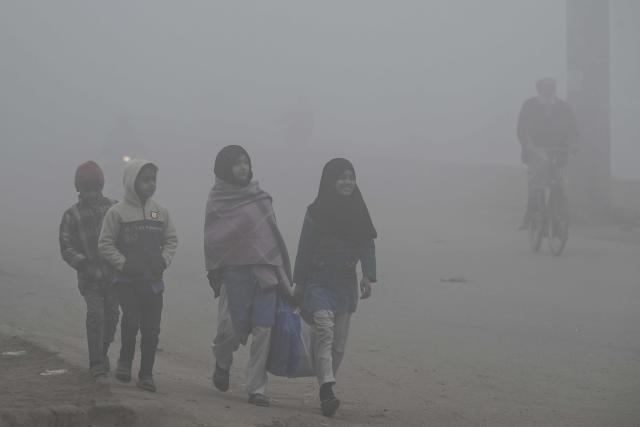 Children walk to school amid dense smog in Lahore December 16, 2025. (Photo by Arif ALI / AFP)