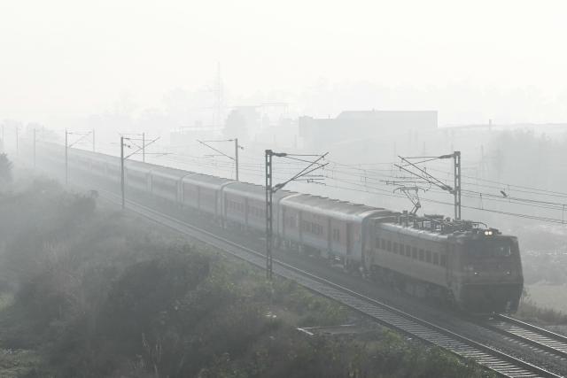 A train runs along a railway track amid dense smog on the outskirts of Amritsar on December 16, 2025.  (Photo by Narinder NANU / AFP)