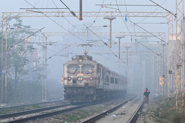 A train runs along a railway track amid dense smog on the outskirts of Amritsar on December 16, 2025.  (Photo by Narinder NANU / AFP)