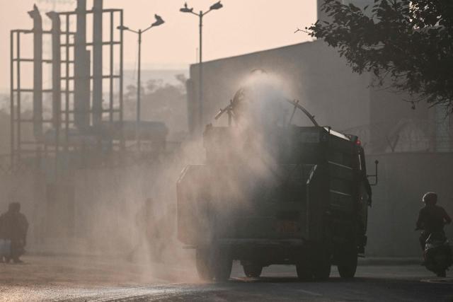 A vehicle of the Public Works Department (PWD) sprays water using an anti-smog gun to curb air pollution in New Delhi on December 16, 2025. (Photo by Arun SANKAR / AFP)