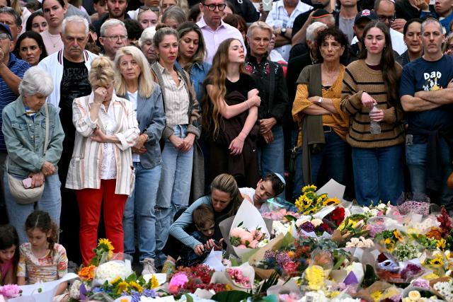 Family members of victims react as they stand with other mourners near tributes at the Bondi Pavilion in memory of the victims of a shooting at Bondi Beach, in Sydney on December 16, 2025. Australia's leaders have agreed to toughen gun laws after attackers killed 15 people at a Jewish festival on Bondi Beach, the worst mass shooting in decades decried as antisemitic "terrorism" by authorities. (Photo by Saeed KHAN / AFP)