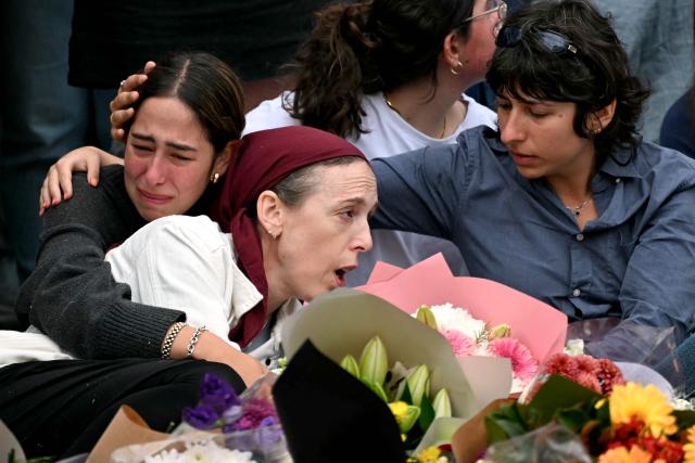 Family members of victims react as they stand with other mourners near tributes at the Bondi Pavilion in memory of the victims of a shooting at Bondi Beach, in Sydney on December 16, 2025. Australia's leaders have agreed to toughen gun laws after attackers killed 15 people at a Jewish festival on Bondi Beach, the worst mass shooting in decades decried as antisemitic "terrorism" by authorities. (Photo by Saeed KHAN / AFP)