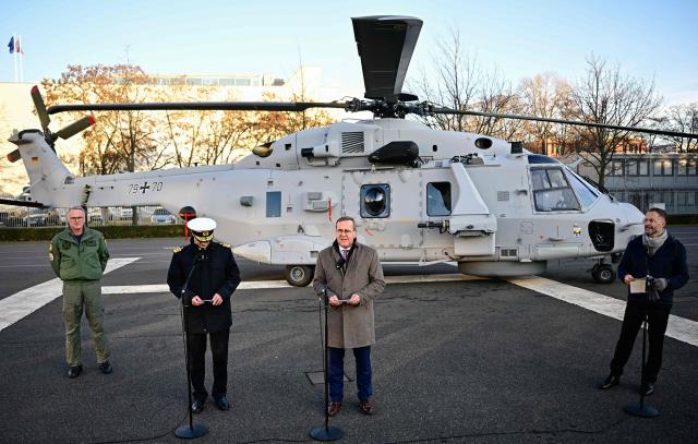 German Defence Minister Boris Pistorius (2ndR) gives a statement in front of a Sea Tiger Sea Tiger shipboard helicopter NH-90 MRFH after it landed in the courtyard of the Defence ministry prior to a handing over ceremony of the first of these helicopters to the German Navy, on December 16, 2025 in Berlin. The Sea Tiger is a high-performance and versatile shipborne helicopter, developed for national and alliance defense. A total of 30 NH-90 MRFH Sea Tiger helicopters will be stationed with Naval Air Wing 5 in Nordholz, Lower Saxony. (Photo by Tobias SCHWARZ / AFP)