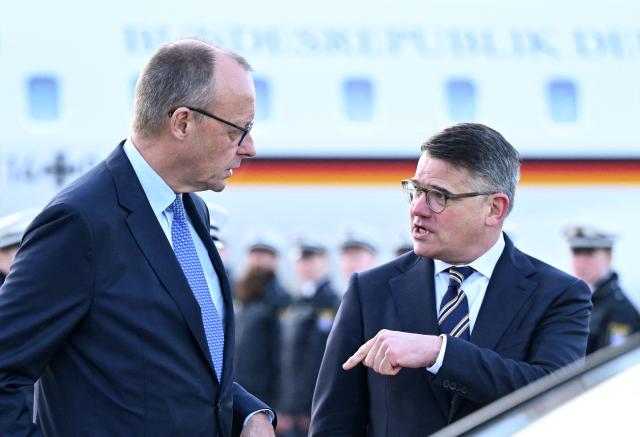 German Chancellor Friedrich Merz (L) speaks with Hesse's State Premier Boris Rhein upon arrival by aircraft at Frankfurt Airport (FRA) in Frankfurt am Main, western Germany on December 16, 2025, as part of his inaugural visit to the German state of Hesse. (Photo by Kirill KUDRYAVTSEV / AFP)