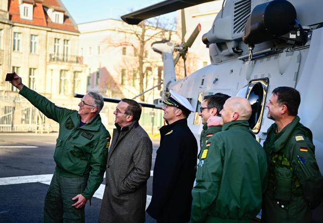 German Defence Minister Boris Pistorius (2ndL) poses for a selfier with  Captain Broder Nielsen (L) and Vice Admiral Axel Deertz (3rdL), Commander of the German Fleet and Supporting Forces of the German Naval Air Command, and crew members in front of a Sea Tiger Sea Tiger shipboard helicopter NH-90 MRFH after it landed in the courtyard of the Defence ministry prior to a handing over ceremony of the first of these helicopters to the German Navy, on December 16, 2025 in Berlin. The Sea Tiger is a high-performance and versatile shipborne helicopter, developed for national and alliance defense. A total of 30 NH-90 MRFH Sea Tiger helicopters will be stationed with Naval Air Wing 5 in Nordholz, Lower Saxony. (Photo by Tobias SCHWARZ / AFP)