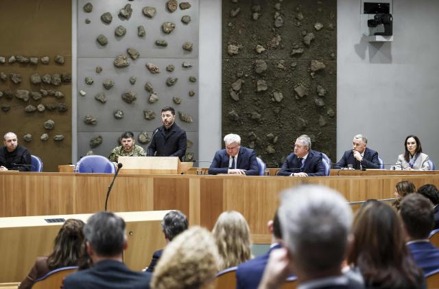 Secretary of the National Security and Defense Council of Ukraine Rustem Umerov (L) reacts as Ukrainian President Volodymyr Zelensky delivers a speech next to Ukrainian Foreign Minister Andrii Sybiha at the Dutch House of Representatives in The Hague, on December 16, 2025. Zelensky is in The Hague for a conference discussing compensations for Ukraine for the consequences of Russian aggression. (Photo by Robin VAN LONKHUIJSEN / ANP / AFP) / Netherlands OUT