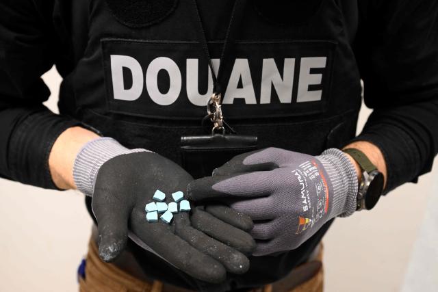 A Belgian customs officer displays ecstasy pills (MDMA) seized at Brussels Airport (Zaventem), during a press conference intended to present an overview of drug seizures in 2025, in Machelen on December 16, 2025. (Photo by Nicolas TUCAT / AFP)