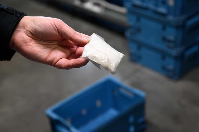 A customs officer displays a cocaine bag seized at Brussels Airport (Zaventem), during a press conference intended to present an overview of drug seizures in 2025, in Machelen on December 16, 2025. (Photo by Nicolas TUCAT / AFP)
