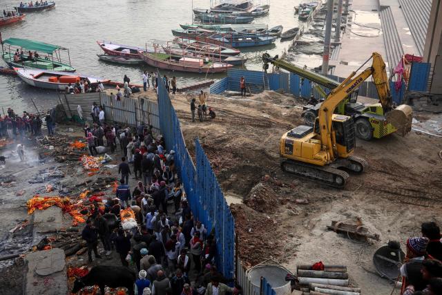 Relatives carry the deceased for funeral rites as construction work goes on at Manikarnika Ghat along the banks of the river Ganges in Varanasi on December 16, 2025. (Photo by Niharika KULKARNI / AFP)