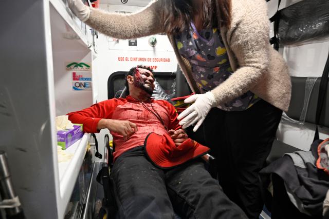 A supporter who was injured during an eviction by the National Civil Police and the Military Police of Public Order (PMOP), is assisted at an ambulance in the surroundings of the National Institute of Professional Training (INFOP), where the National Electoral Council (CNE) will carry out the scrutiny, after the vote count was interrupted several times due to computer failures, in Tegucigalpa on December 16, 2025. At least eight people were injured on Monday night during an operation to remove left-wing militants who were pressing for the final results of the general elections in Honduras, authorities reported on Tuesday. More than two weeks after the elections, Hondurans still do not know the winner of the presidential race or other elected officials in positions such as mayor of the capital, Tegucigalpa. (Photo by Orlando SIERRA / AFP)