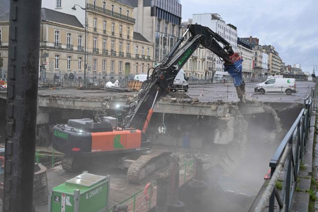 Workers use an excavator, mounted on a barge, to chip away the slab of a car park and uncover the Vilaine river, in the city centre of Rennes, western France on December 16, 2025. (Photo by Damien MEYER / AFP)